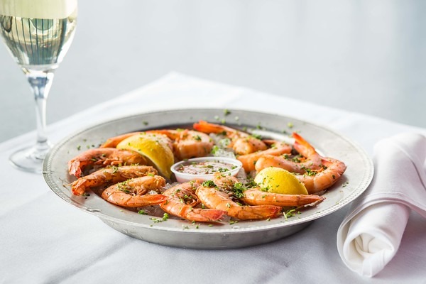 Chilled peel-and-eat boiled shrimp on ice with lemon and cocktail sauce