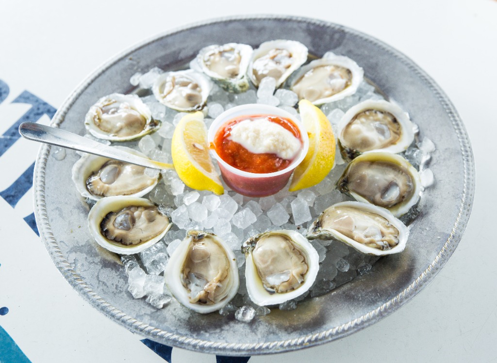 Fresh raw oysters on the half shell with cocktail sauce and lemon
